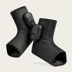 NACRE FORM™ cordless air compression foot and ankle massager displayed as a pair of black wearable massage boots against a warm cream background. Each electric foot massager features a textured fabric exterior, integrated digital control panel, adjustable massage functions and front zip fastening. The product photograph presents a rechargeable heated foot massage device with comfortable ankle coverage, portable construction and personalised compression settings for convenient home relaxation.