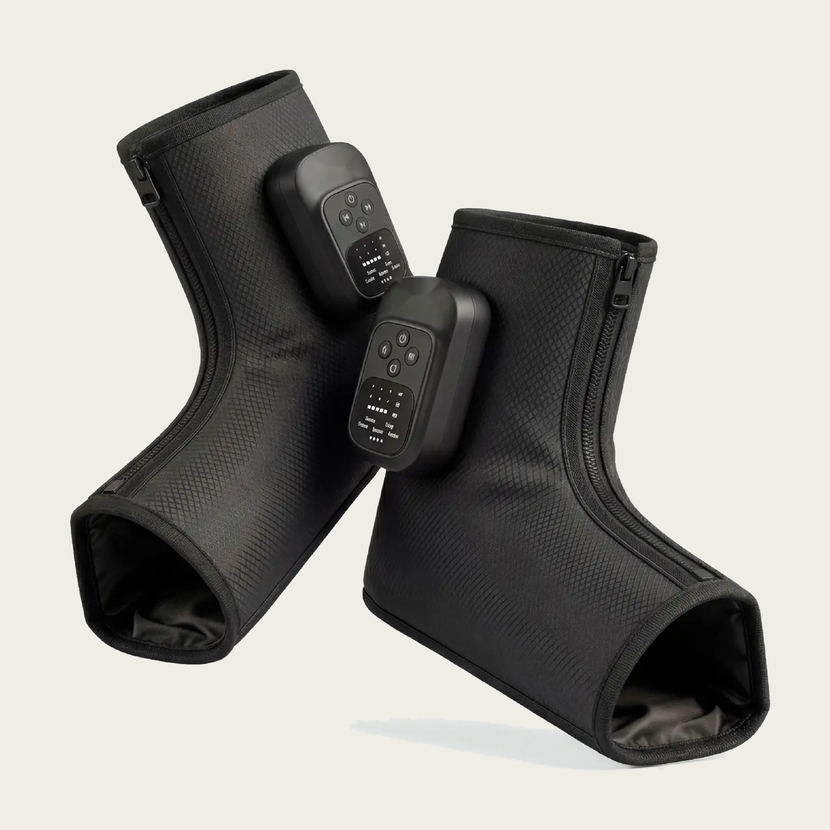 NACRE FORM™ cordless air compression foot and ankle massager displayed as a pair of black wearable massage boots against a warm cream background. Each electric foot massager features a textured fabric exterior, integrated digital control panel, adjustable massage functions and front zip fastening. The product photograph presents a rechargeable heated foot massage device with comfortable ankle coverage, portable construction and personalised compression settings for convenient home relaxation.